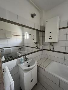 a white bathroom with a sink and a tub at Lidvina Apartman in Nyíregyháza +11 photos