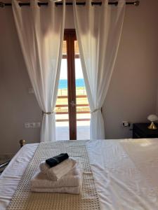 a bedroom with a bed with towels and a window at Anatèlia Beach House in Portianón
