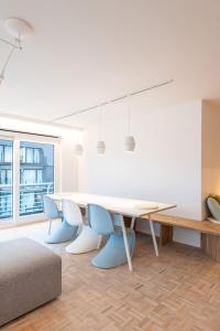a dining room with a white table and blue chairs at -Stay- at Oostduinkerke in Oostduinkerke