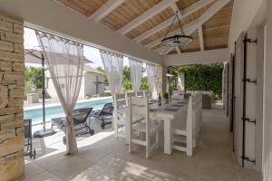 a dining room with a table and chairs and a pool at Villa Batelica with large garden, kids playground and private pool in Labin +50 photos