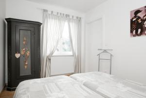a white bedroom with a bed and a window at Gîte 3 - les Champêtres in Mittelwihr