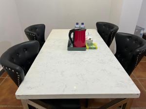 une table blanche avec des chaises et une cafetière. dans l'établissement Paramount B&B, à Kinshasa
