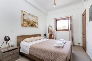 a white bedroom with a bed and a window at Utopia suites in the heart of Aegina by 8essentially in Aegina Town