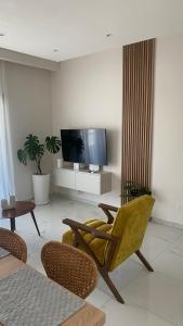 a living room with a flat screen tv and chairs at Kyra apartment in Polis Chrysochous