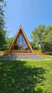 a building with a wooden roof on top of a grass field at Old Nut Cabin in Teşila