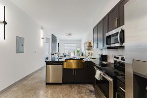 Una cocina con gabinetes negros y un fregadero dorado. en Modern 2BR, Family-Friendly in FLL, Near Beach!, en Fort Lauderdale 30 fotos más