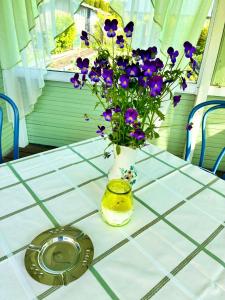 Una mesa con un jarrón con flores moradas. en HelmiLoma, en Pärnu 37 fotos más