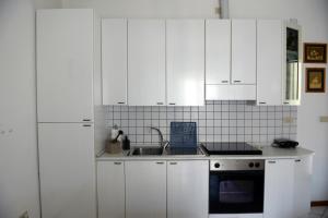 a white kitchen with white cabinets and a sink at Appartamento Climatizzato con Piscina Ca' Aurelia in Lido di Savio