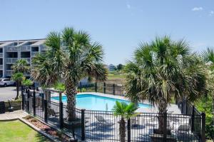 a swimming pool with palm trees in front of a building at Hook, Line and Two Stinkers by Bryant Real Estate in Carolina Beach