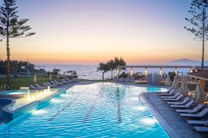 马斯蒂查里Zeus Kos Beach的带椅子的游泳池和背景中的海洋