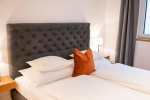 a bed with white sheets and orange pillows at Obersulzberggut in Radstadt