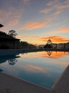 a swimming pool with a sunset in the background at Refúgio Premium nas Montanhas de Alfredo Chaves Refúgio nas Montanhas de Alfredo Chaves com Piscina Jacuzzi Aquecida externa Suite Master com Hidro e Área Gourmet in Alfredo Chaves