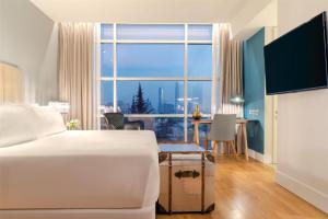 a hotel room with a bed and a large window at NH Collection Santiago Casacostanera in Santiago