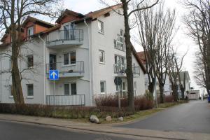 un edificio bianco con un cartello blu davanti di Ferienwohnung Preiss a Sassnitz