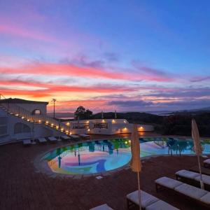 a hotel with a pool with a sunset in the background at Hotel Pedra Santa in Baja Sardinia