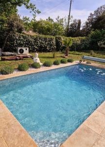 a swimming pool with blue water in a yard at Logement cosy avec piscine chauffée, jacuzzi, jardin et climatisation in Flayosc