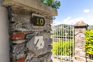 a stone wall with a clock on it next to a gate at Gelsomini appartamenti sul lago dOrta in Orta San Giulio