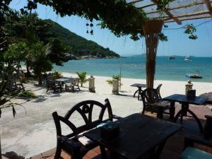 Un grupo de mesas y sillas en la playa. en Secluded Villa with Private Pool and Breathtaking Sea Views, en Ban Thong Phlu