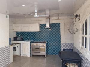 a kitchen with white cabinets and blue tiles on the wall at Studio55 in Lomé +21 photos