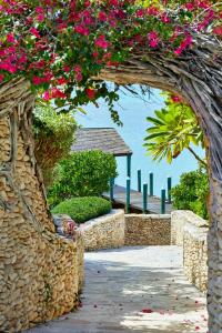 a stone archway with pink flowers on a beach at French Leave Resort, Autograph Collection in Governorʼs Harbour