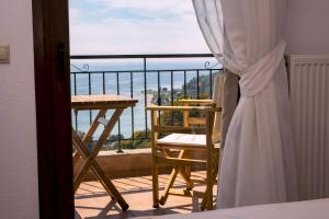a balcony with a table and chair and a view of the ocean at Koumaros Villas in Agia Paraskevi