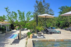a patio with a pool and an umbrella and chairs at Villa Harmonie by Villa Plus in Flassans-sur-Issole