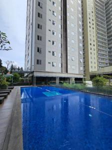 a large blue pool in front of two tall buildings at Hegarmanah Residence Apartment in Bandung
