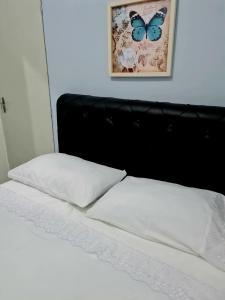 Una cama con un cabecero negro con una mariposa. en Pousada Martino, en Praia Grande