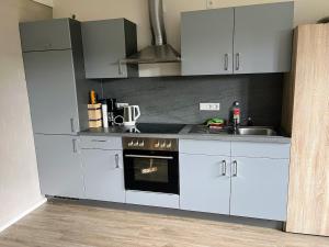 a kitchen with white cabinets and a stove and a sink at Hempen Fied Gästehaus - Apartment 2 in Bad Zwischenahn