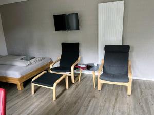 a room with two chairs and a bed and a tv at Hempen Fied Gästehaus - Apartment 2 in Bad Zwischenahn +19 photos