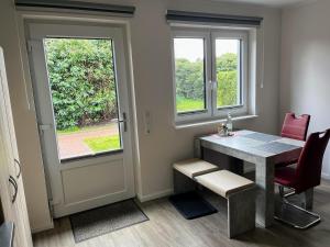 a dining room with a table and two windows at Hempen Fied Gästehaus - Apartment 2 in Bad Zwischenahn