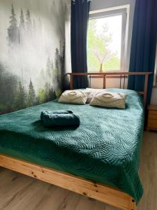 a bed with a green comforter in a bedroom at Bezdroża Mazurskie in Mrągowo