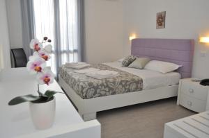 a bedroom with a bed and a vase with flowers at Hotel Sikania in San Vito lo Capo
