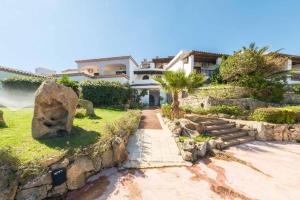 a house with a stone wall and a yard at Hotel Pedra Santa in Baja Sardinia