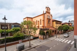 an old church with a clock tower on a street at Little Yellow House in Gijón