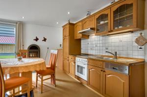 a kitchen with wooden cabinets and a table with a sink at Ferienwohnung Christa in Mauth +12 photos