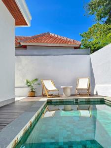 ヌサドゥアにあるKia Kaha Peaceful 2BR 2BA Villa with Pool in Bukitの家の隣に椅子2脚付きのスイミングプール