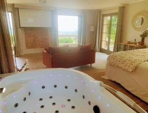 a bath tub in a bedroom with a bed at L'instant Beaujolais 2 ou 4 personnes Logis cosy balnéo vue jardin in Theizé