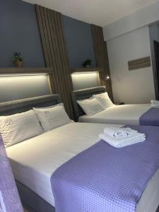 Dos camas en una habitación de hotel con toallas encima. en Avra Comfort Rooms - Family, en Nea Potidaea
