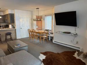 a living room with a table and a tv on a wall at Pico F101 in Killington +13 photos