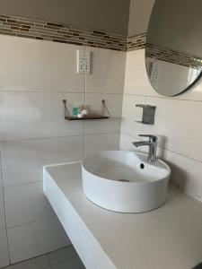 Un baño blanco con lavabo y espejo. en Tlou- Sejie Hotel, en Palapye 11 fotos más