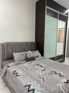 a bedroom with a bed with a gray bedspread and a window at Putra Impiana Puchong in Puchong
