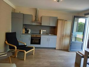 a kitchen with white cabinets and a chair in a room at Hempen Fied Gästehaus - Apartment 1 in Bad Zwischenahn