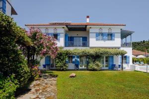 ein großes weißes Haus mit blauen Fenstern und einem Garten in der Unterkunft Aktaion Hotel in Kalamos + 44 Fotos