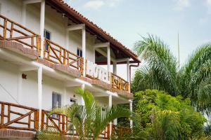 a building with wooden balconies and palm trees at Hotel Hacienda Rincon del Cielo in Curití