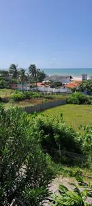 a view of a field with trees and the ocean at Vistamar Arco das Flores in Taíba