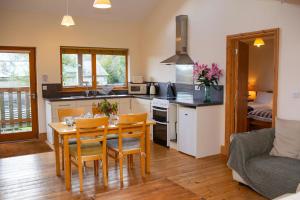 a kitchen and dining room with a table and chairs at Owls Roost Eco Lodge Apartment Lampeter in Lampeter