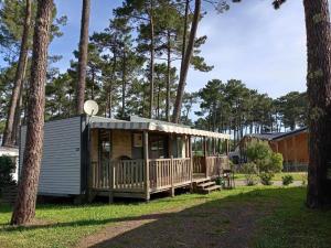 a small cabin with a porch and trees at KOKUA VACANCES Mobil Homes Résidentiels camping 4 étoiles JULIEN EN BORN in Saint-Julien-en-Born