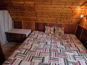 a bed in a room with a quilt on it at Chata v lese pri rieke Bela in Pribylina