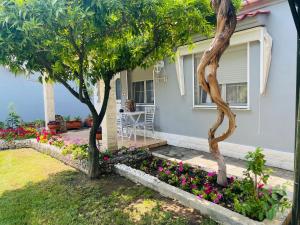 a house with two trees and flowers in the yard at The Little Blooming House in Agíasma